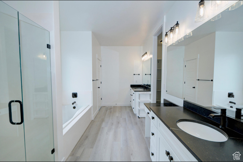 Bathroom featuring dual bowl vanity, a washtub, and hardwood / wood-style flooring
