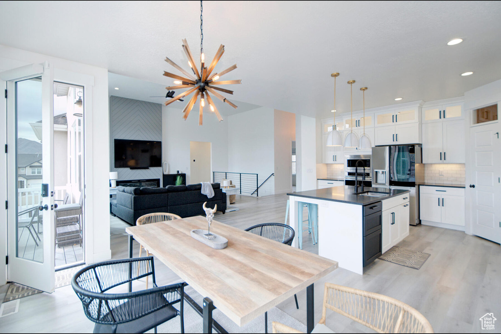 Kitchen featuring a kitchen island with sink, a notable chandelier, white cabinetry, and pendant lighting
