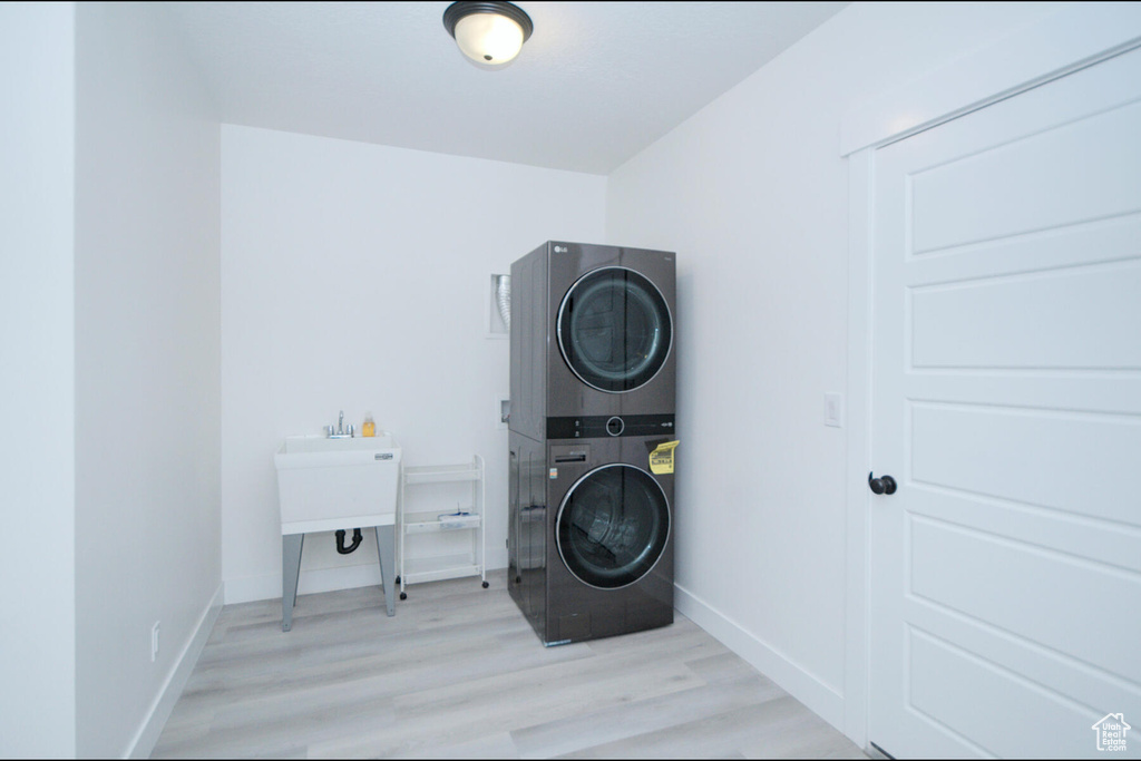 Washroom featuring light wood-type flooring and stacked washer and clothes dryer
