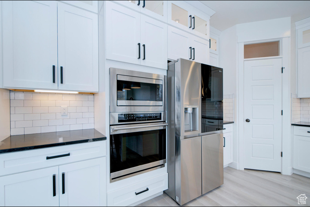 Kitchen featuring backsplash, white cabinetry, light hardwood / wood-style floors, and appliances with stainless steel finishes