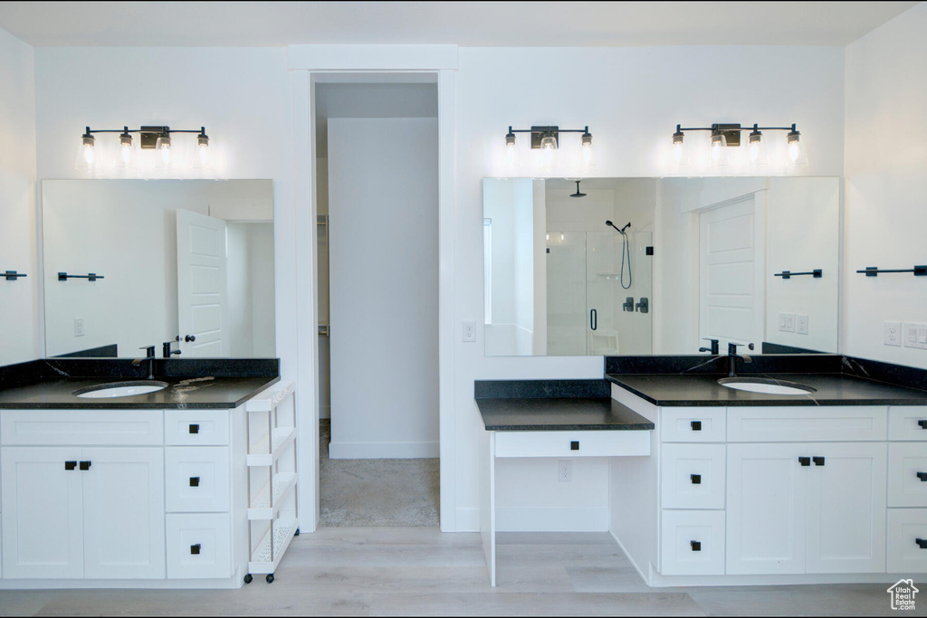 Bathroom featuring walk in shower, double sink vanity, and wood-type flooring