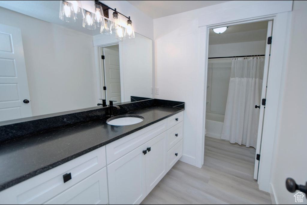 Bathroom featuring hardwood / wood-style flooring, shower / bathtub combination with curtain, and vanity