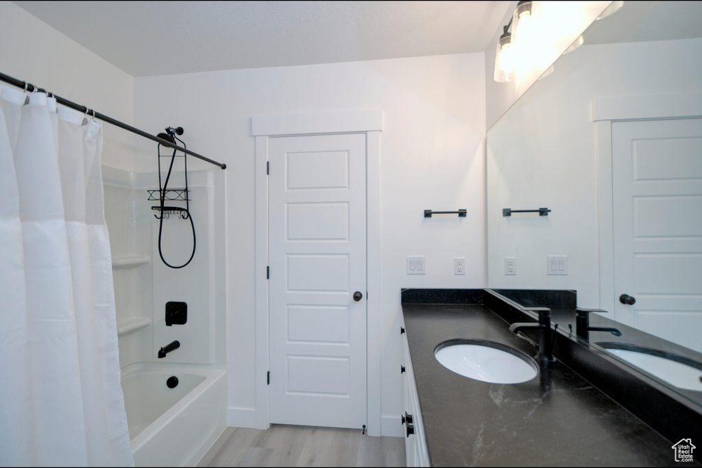Bathroom featuring hardwood / wood-style floors, vanity, and shower / bath combo