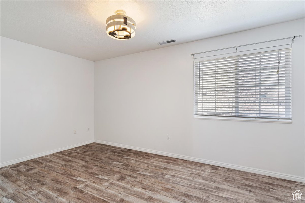 Empty room with hardwood / wood-style flooring and a textured ceiling