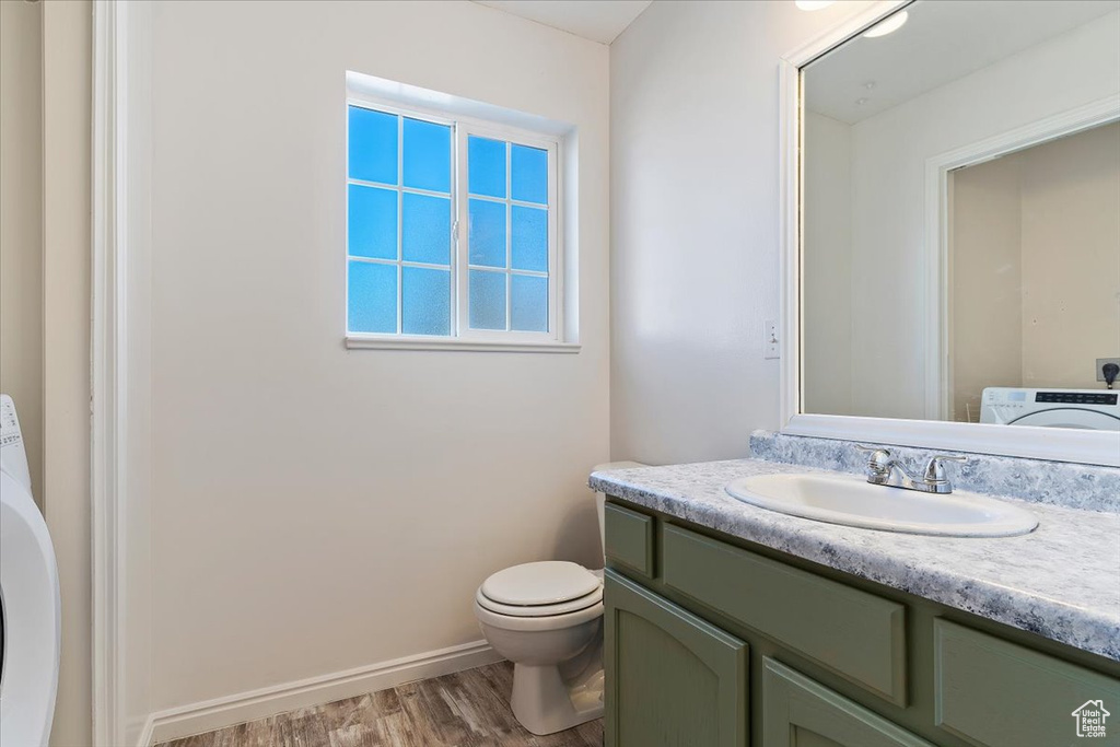 Bathroom with vanity, toilet, washer / dryer, and hardwood / wood-style flooring
