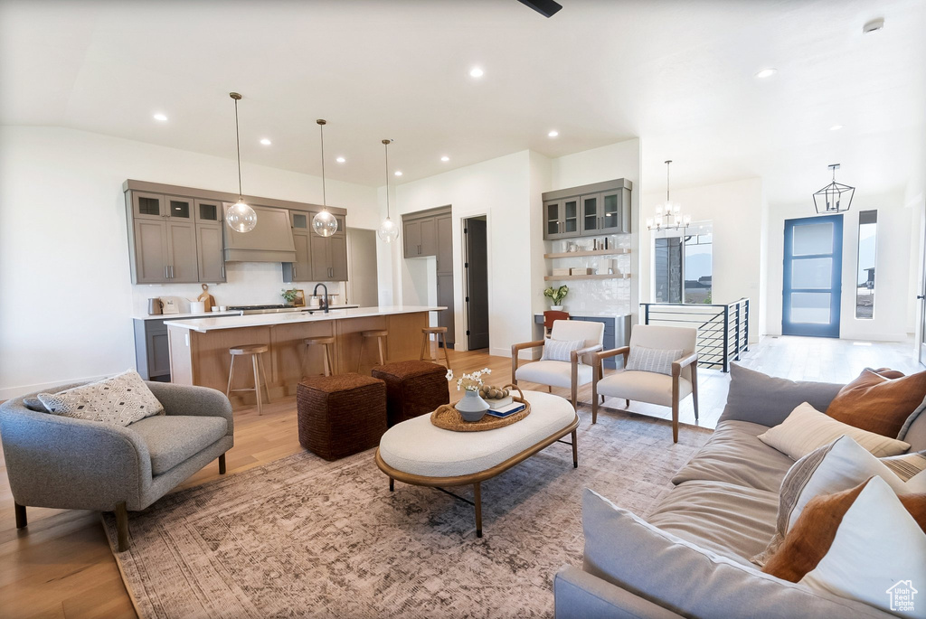 Living room with an inviting chandelier, sink, and light hardwood / wood-style flooring