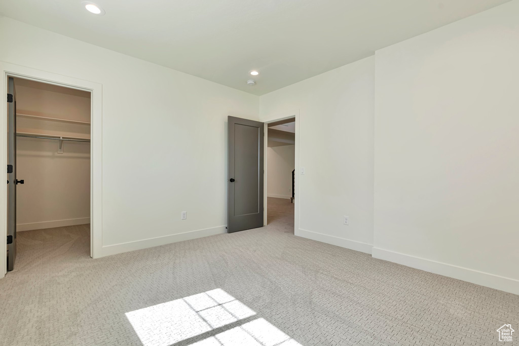 Unfurnished bedroom featuring a closet, a walk in closet, and light colored carpet