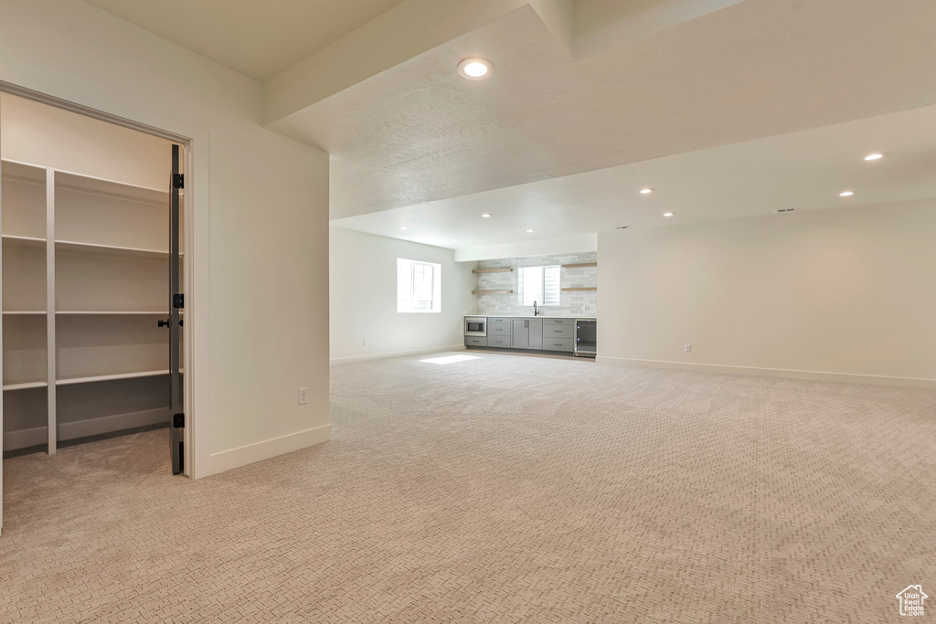 Unfurnished living room with light colored carpet and sink