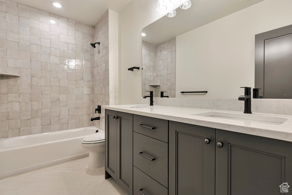 Full bathroom with double sink, tiled shower / bath, tile flooring, toilet, and oversized vanity