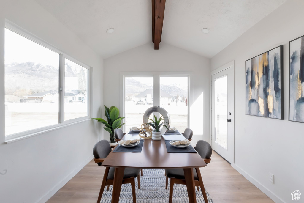 Dining space featuring a mountain view, vaulted ceiling with beams, and light hardwood / wood-style floors