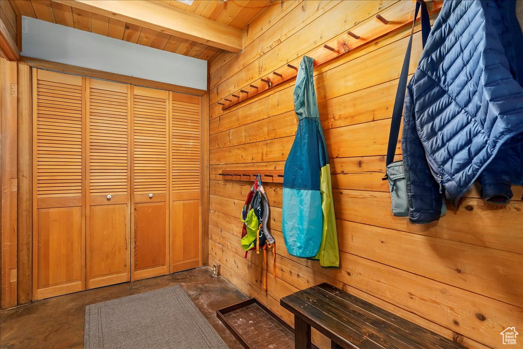 Mudroom featuring wood ceiling, beam ceiling, and wood walls