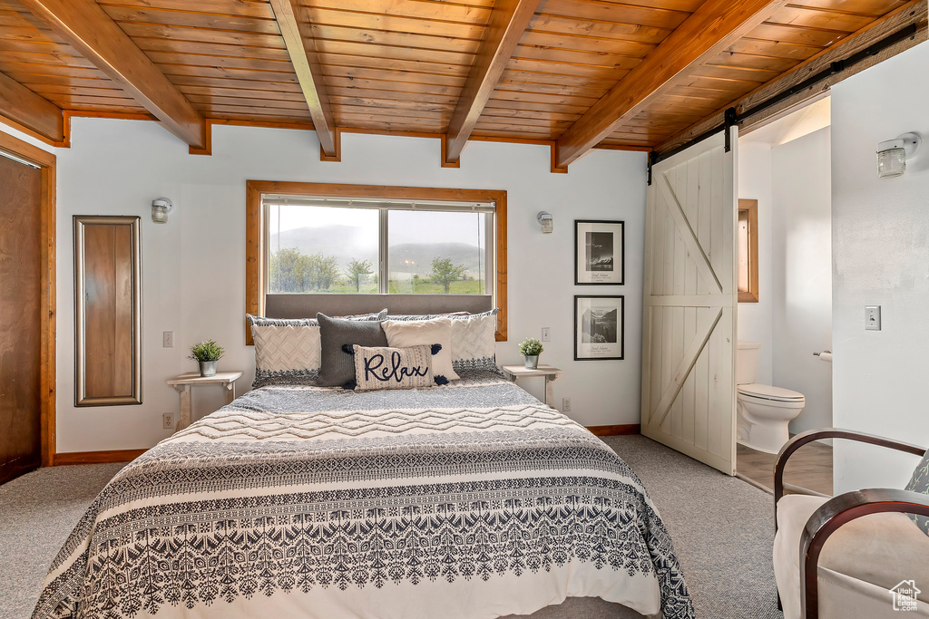 Carpeted bedroom featuring ensuite bathroom, beamed ceiling, a barn door, and wooden ceiling