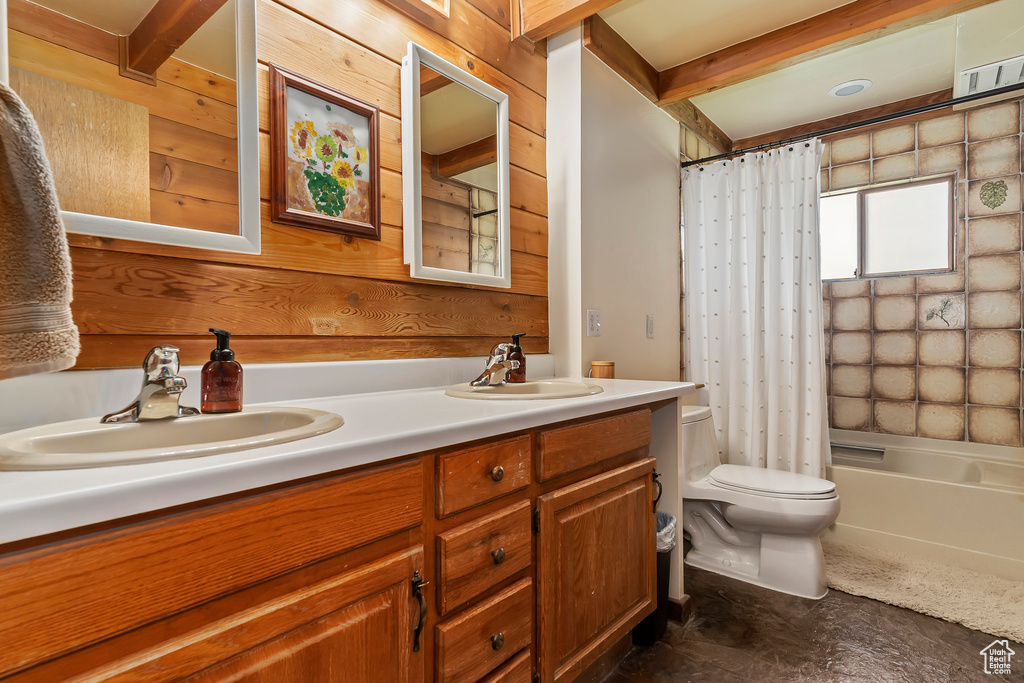 Full bathroom with shower / bath combination with curtain, double vanity, wood walls, toilet, and beamed ceiling