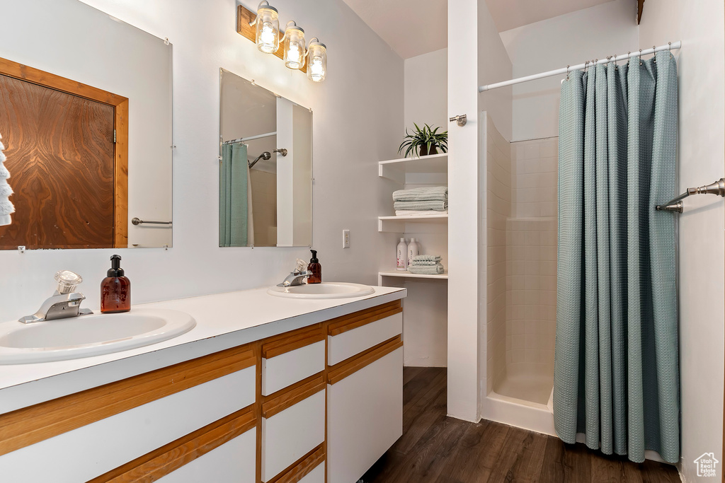 Bathroom featuring a shower with curtain, double sink, hardwood / wood-style flooring, and oversized vanity