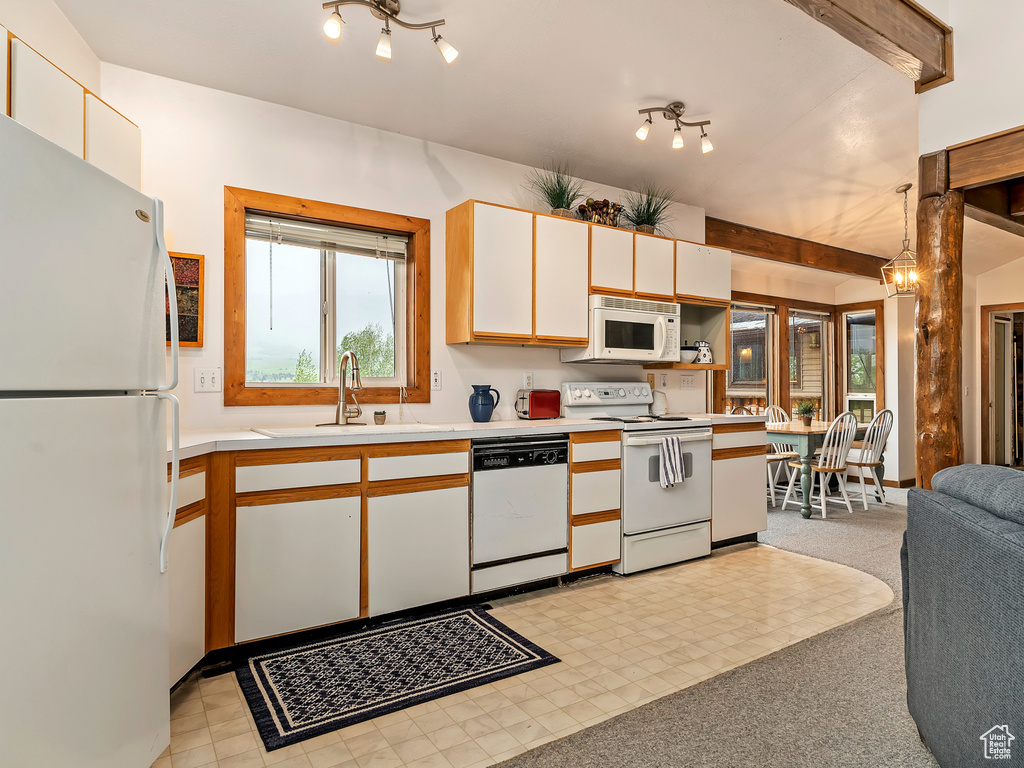 Kitchen with white cabinets, white appliances, beam ceiling, sink, and light colored carpet