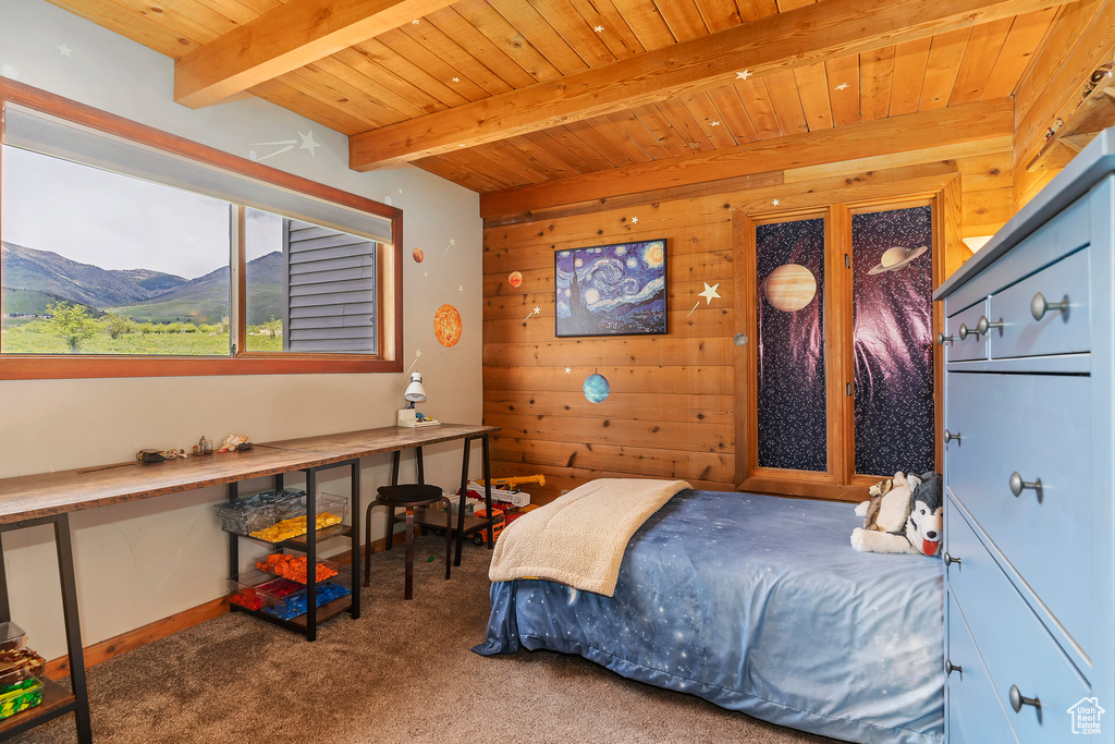 Carpeted bedroom with beam ceiling, wooden ceiling, wood walls, and a mountain view