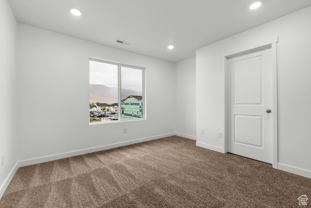 Empty room featuring a mountain view and dark carpet