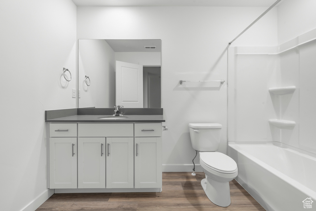 Full bathroom featuring toilet, bathing tub / shower combination, vanity, and hardwood / wood-style flooring