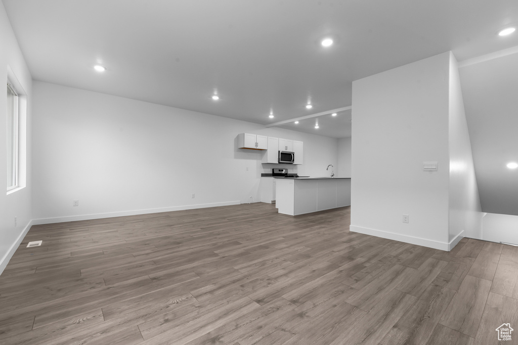 Unfurnished living room featuring sink and light hardwood / wood-style flooring
