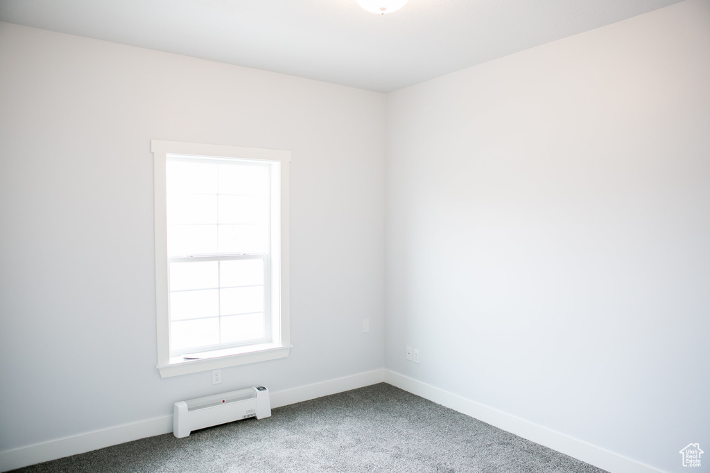 Carpeted empty room featuring a baseboard radiator
