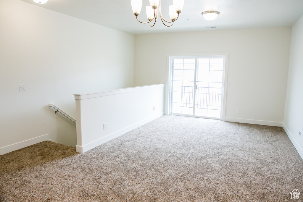 Empty room with light carpet and a notable chandelier