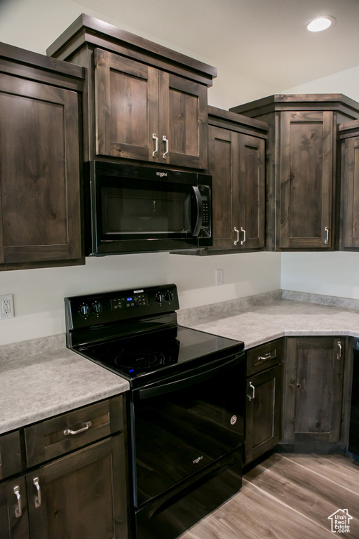 Kitchen featuring dark brown cabinets, black appliances, and light hardwood / wood-style floors