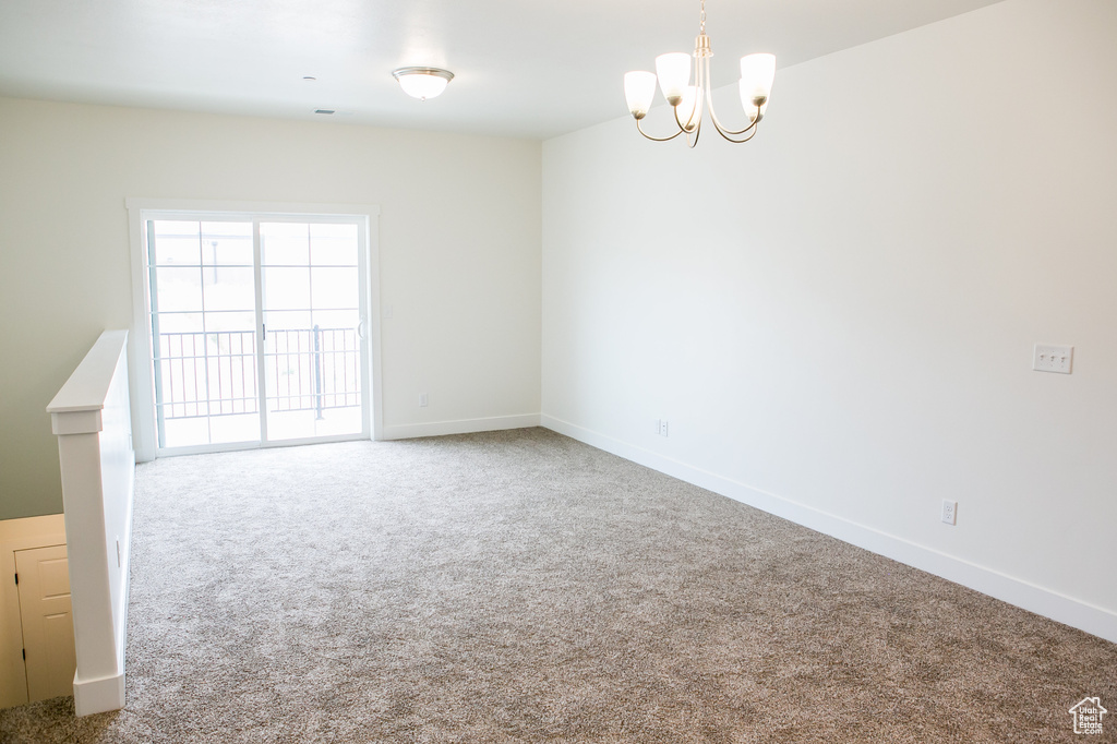Empty room with an inviting chandelier and light carpet