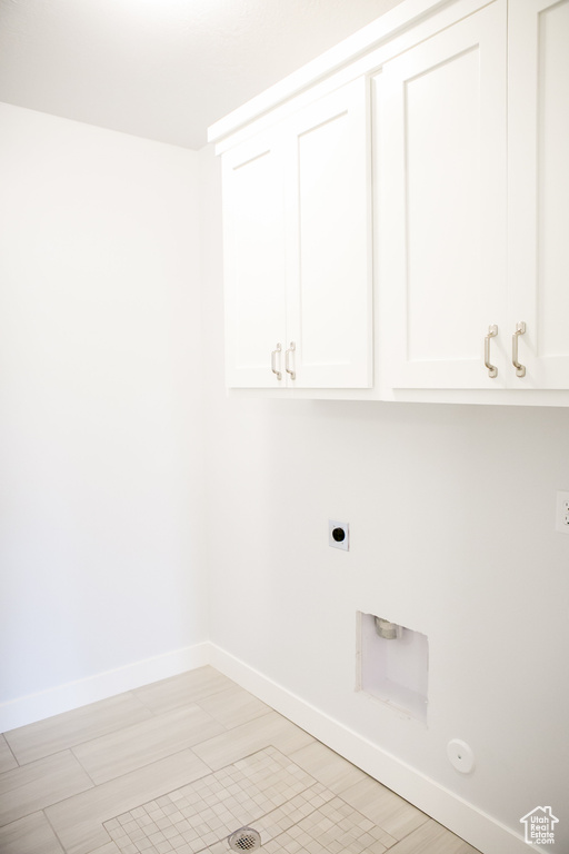 Washroom featuring cabinets, hookup for an electric dryer, gas dryer hookup, and light tile flooring