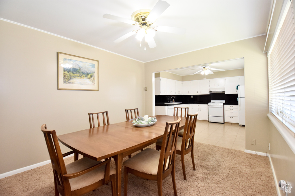 Dining space with sink, light colored carpet, and ceiling fan