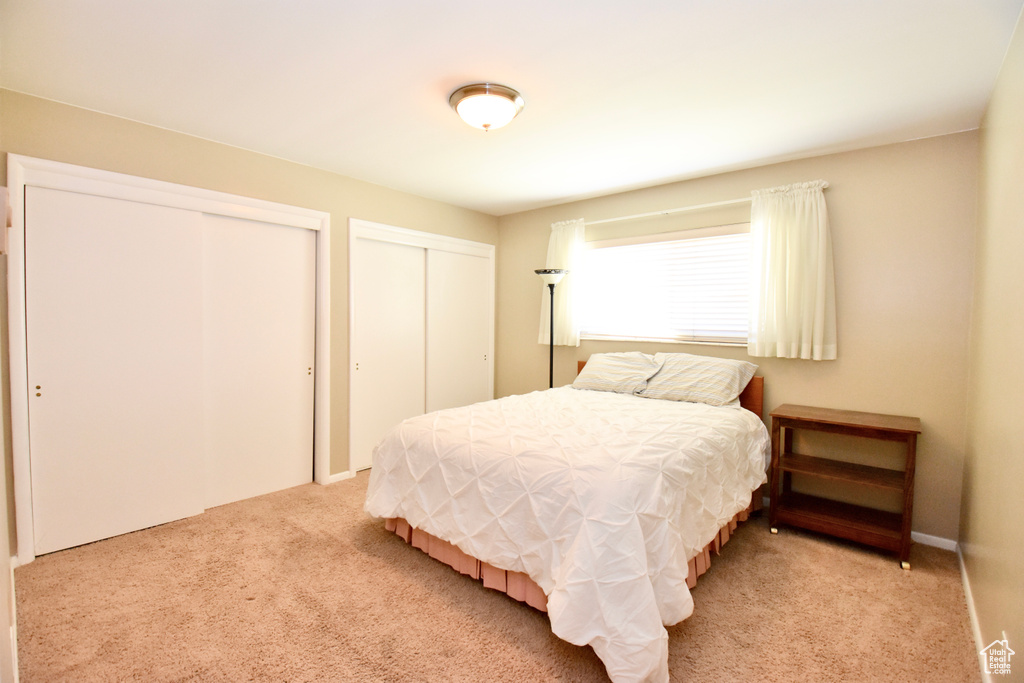Bedroom with multiple closets and light carpet