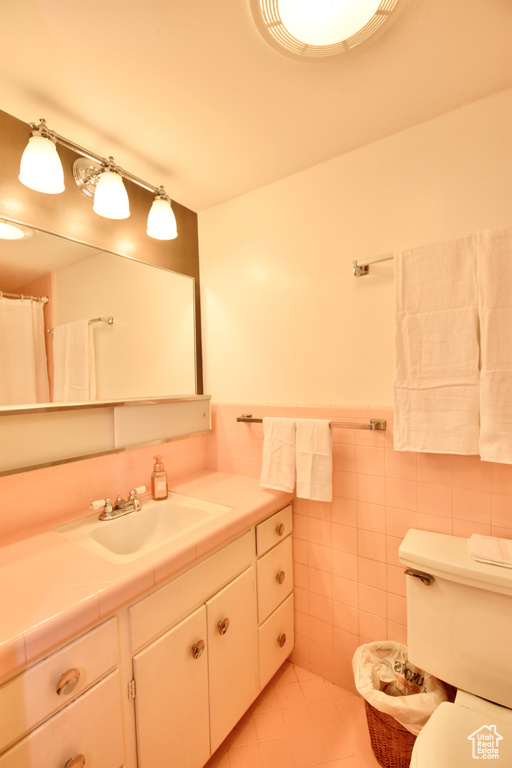 Bathroom featuring tile walls, tile floors, vanity, and toilet