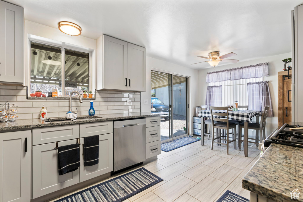 Kitchen with tasteful backsplash, stainless steel dishwasher, and a healthy amount of sunlight