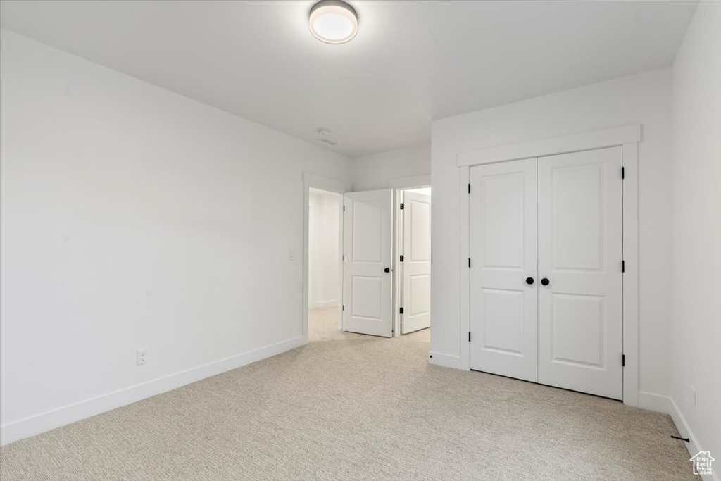 Unfurnished bedroom featuring a closet and light colored carpet