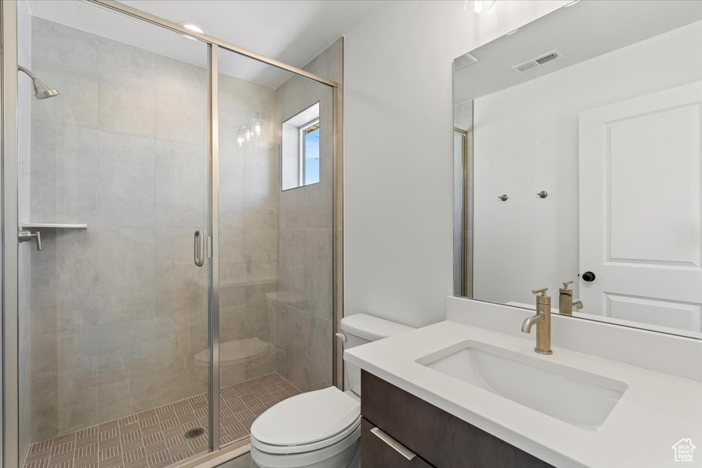 Bathroom with vanity, toilet, and a shower with door