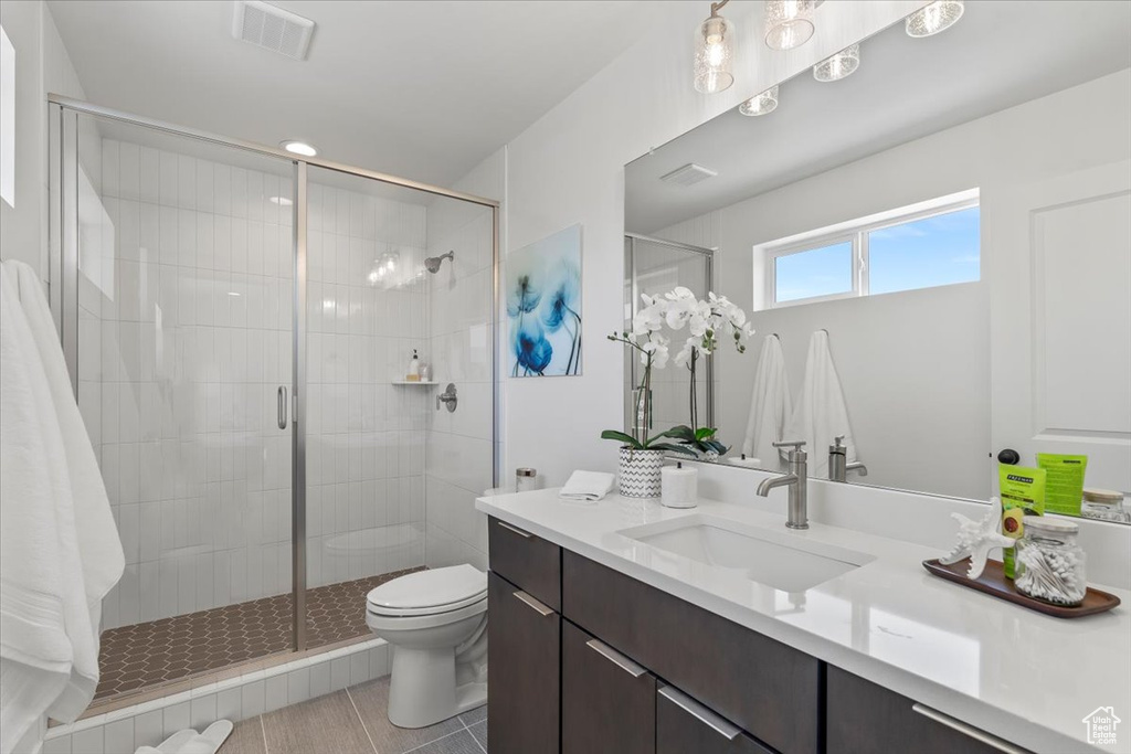 Bathroom featuring vanity, toilet, tile patterned flooring, and walk in shower