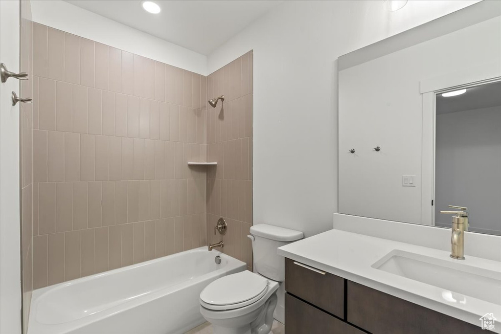 Full bathroom featuring vanity, tiled shower / bath combo, and toilet