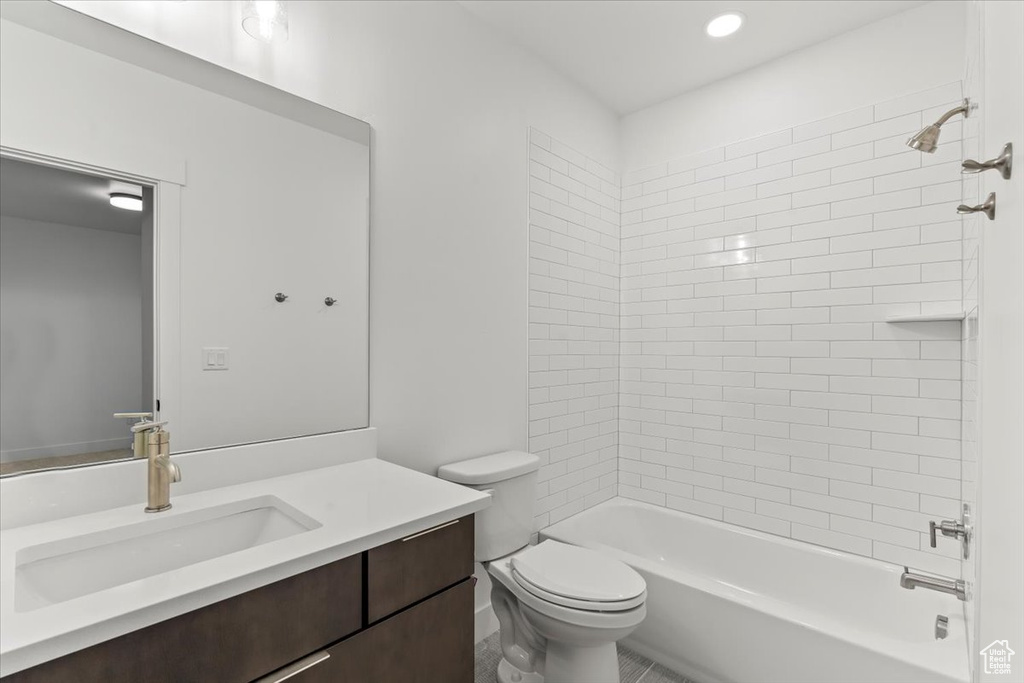 Full bathroom with toilet, tile patterned floors, tiled shower / bath combo, and vanity