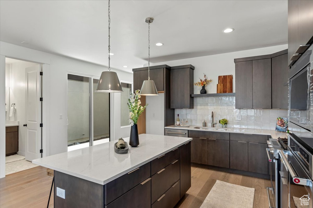 Kitchen featuring light hardwood / wood-style floors, decorative light fixtures, tasteful backsplash, and a kitchen island