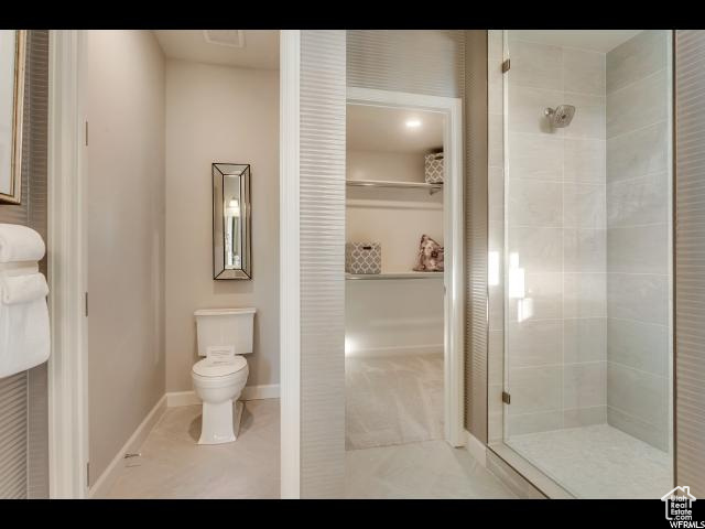 Bathroom with tile floors, a shower with shower door, and toilet
