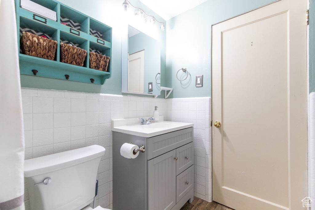 Bathroom featuring backsplash, wood-type flooring, vanity, tile walls, and toilet