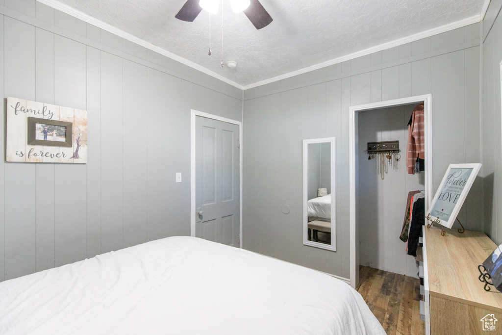 Bedroom with dark hardwood / wood-style flooring, a closet, ceiling fan, and crown molding