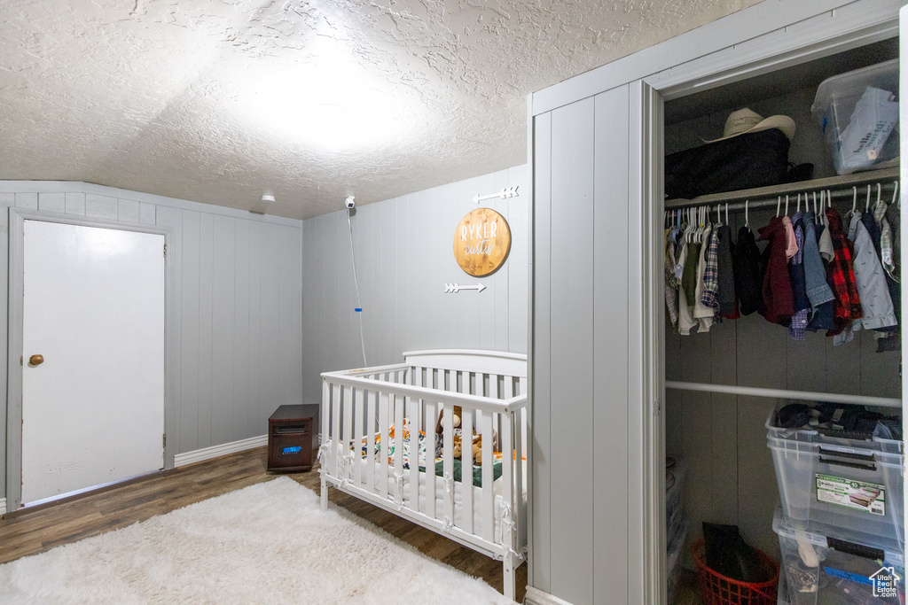 Bedroom featuring a closet, dark hardwood / wood-style flooring, a textured ceiling, and a nursery area
