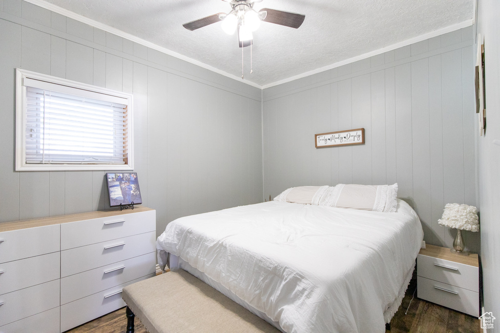Bedroom featuring a textured ceiling, ornamental molding, dark wood-type flooring, and ceiling fan