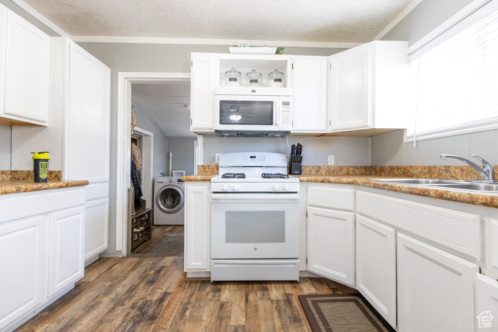 Kitchen with white cabinets, white appliances, washer / clothes dryer, sink, and dark wood-type flooring