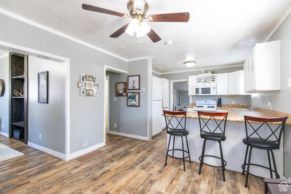 Kitchen with white appliances, kitchen peninsula, and dark hardwood / wood-style floors