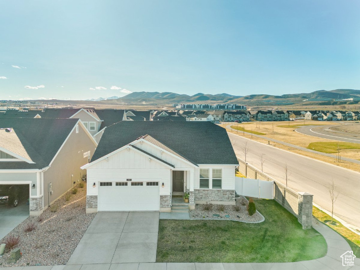 View of front of house featuring a mountain view, a garage, and a front lawn