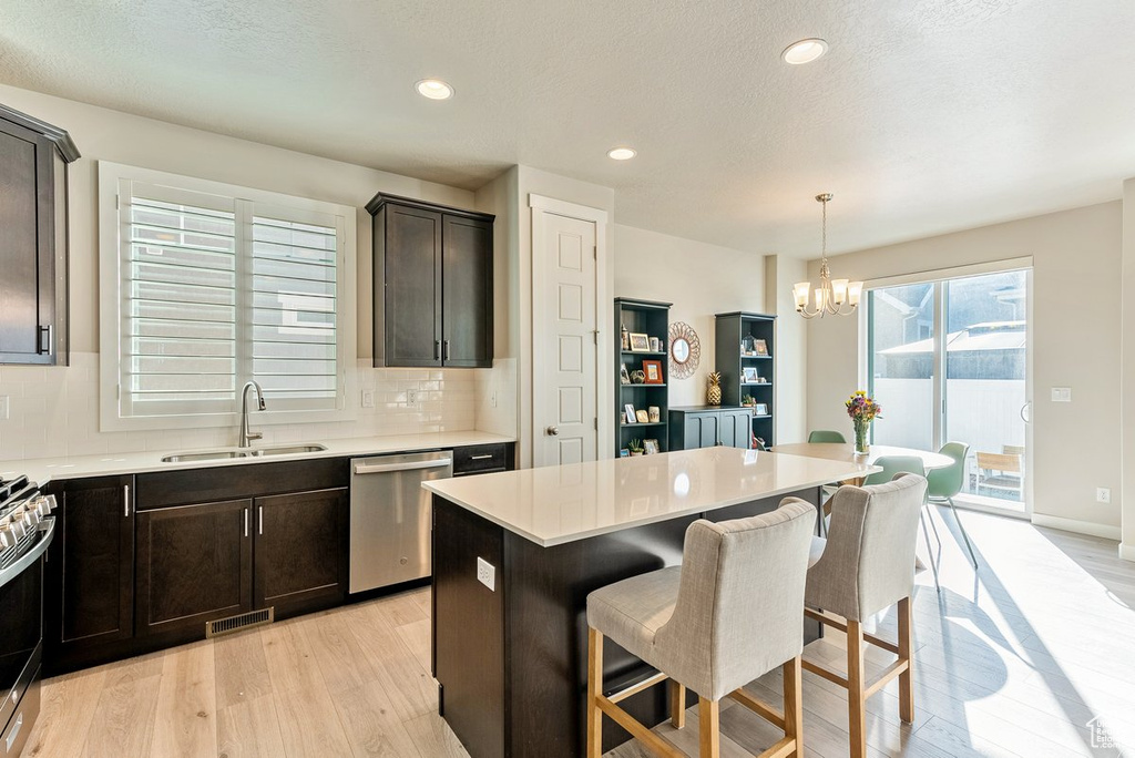 Kitchen featuring light hardwood / wood-style floors, a center island, stainless steel appliances, a chandelier, and sink
