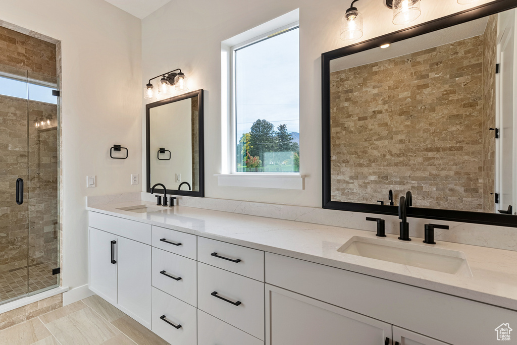 Bathroom featuring double vanity, a shower with shower door, and tile flooring