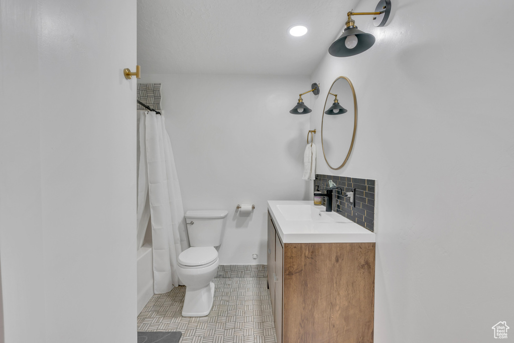 Full bathroom featuring shower / tub combo with curtain, tile flooring, vanity, tasteful backsplash, and toilet