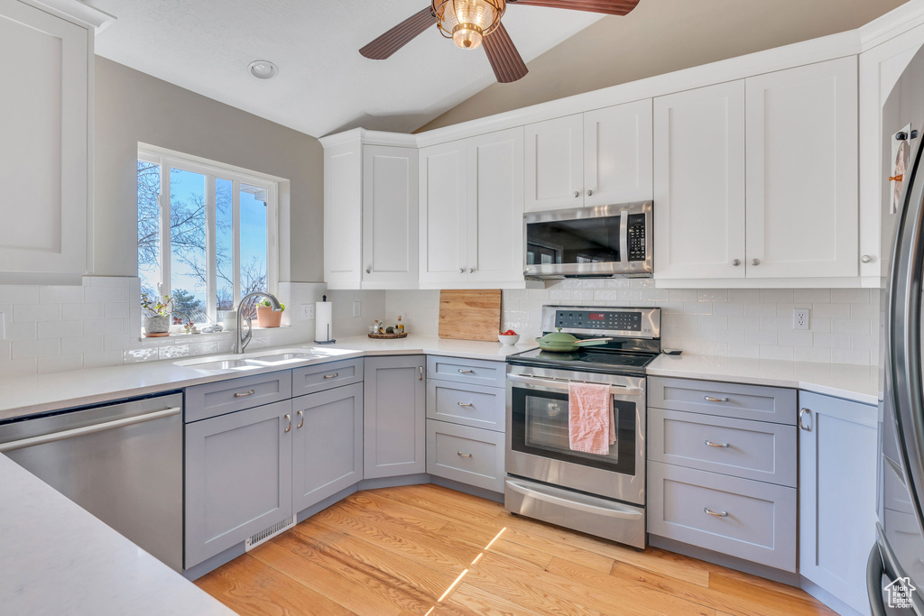 Kitchen featuring light hardwood / wood-style flooring, stainless steel appliances, backsplash, and ceiling fan